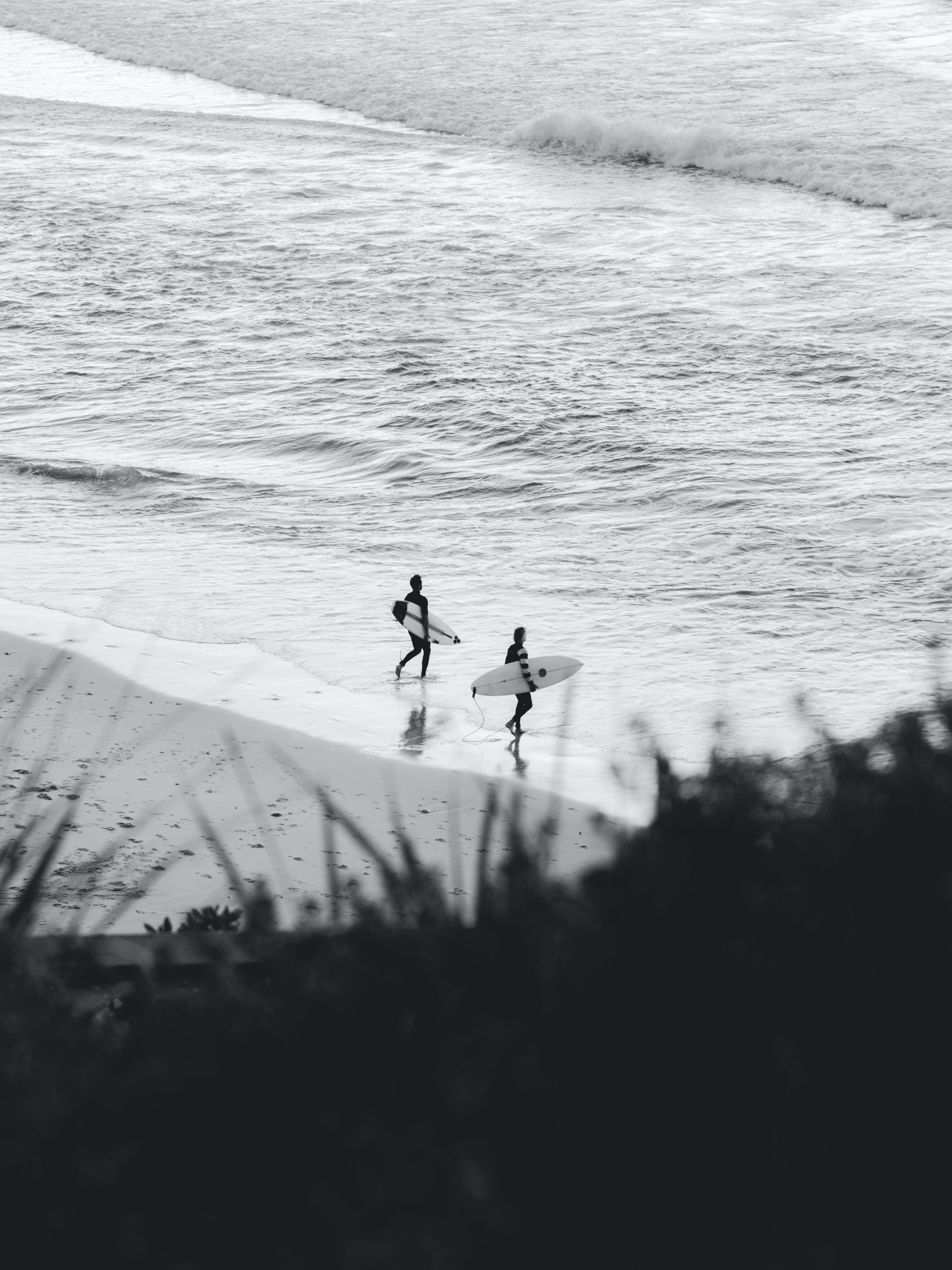 2 surfers running into a wave