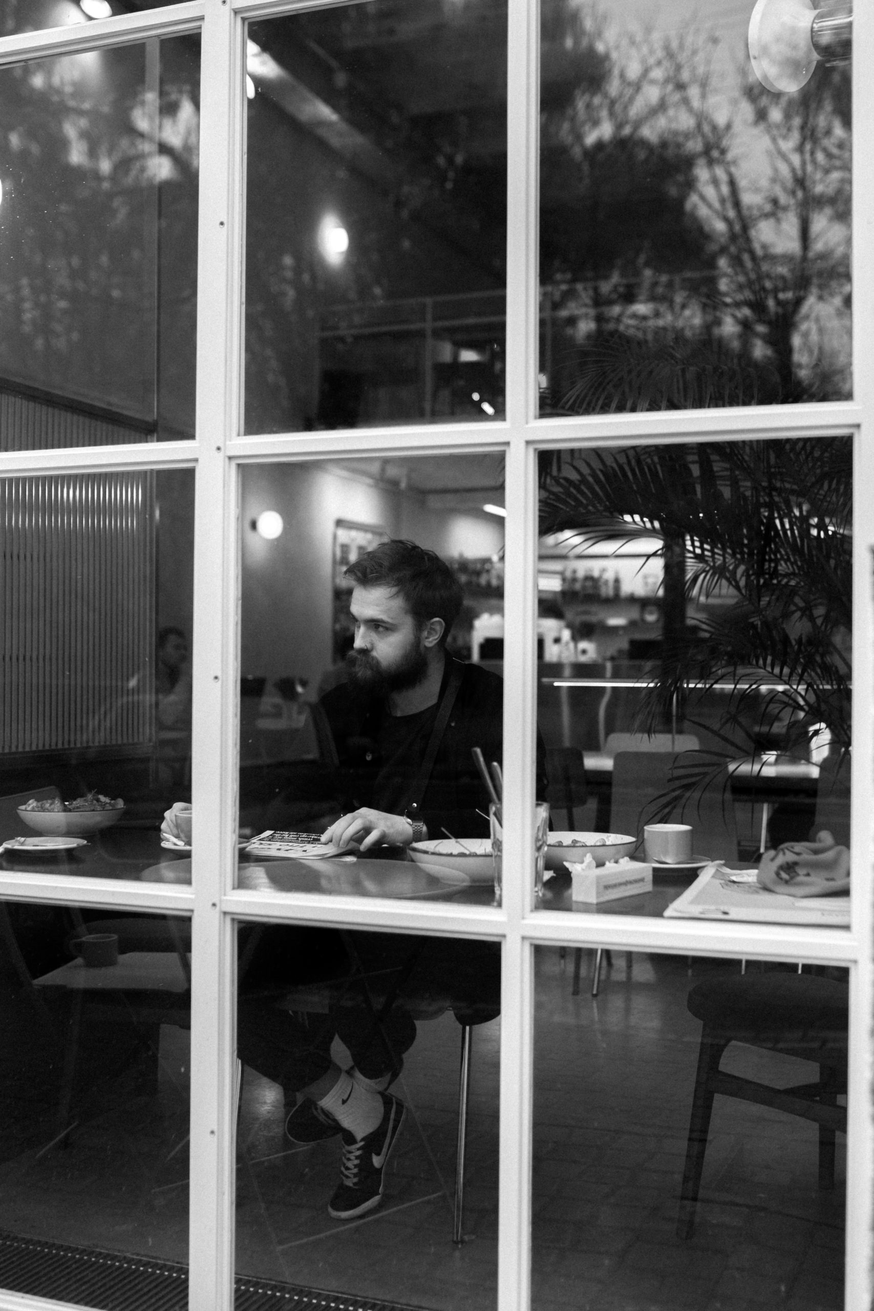 Man sitting alone in a restaurant window in black and white